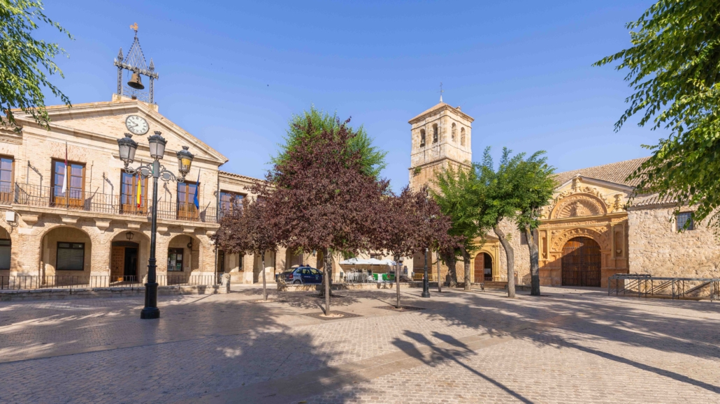 Plaza Mayor de Corral de Almaguer con el Ayuntamiento porticado, la torre de la iglesia y la portada de la iglesia parroquial al fondo