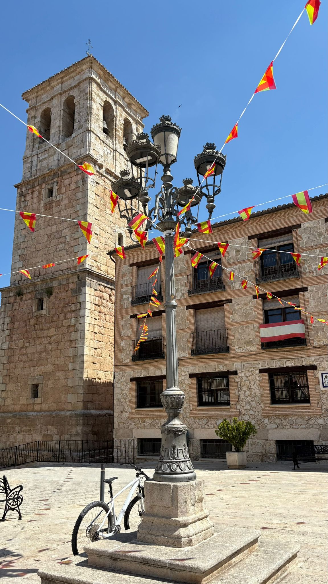 Torre de la iglesia de Corral de Almaguer engalanada con banderolas durante las fiestas